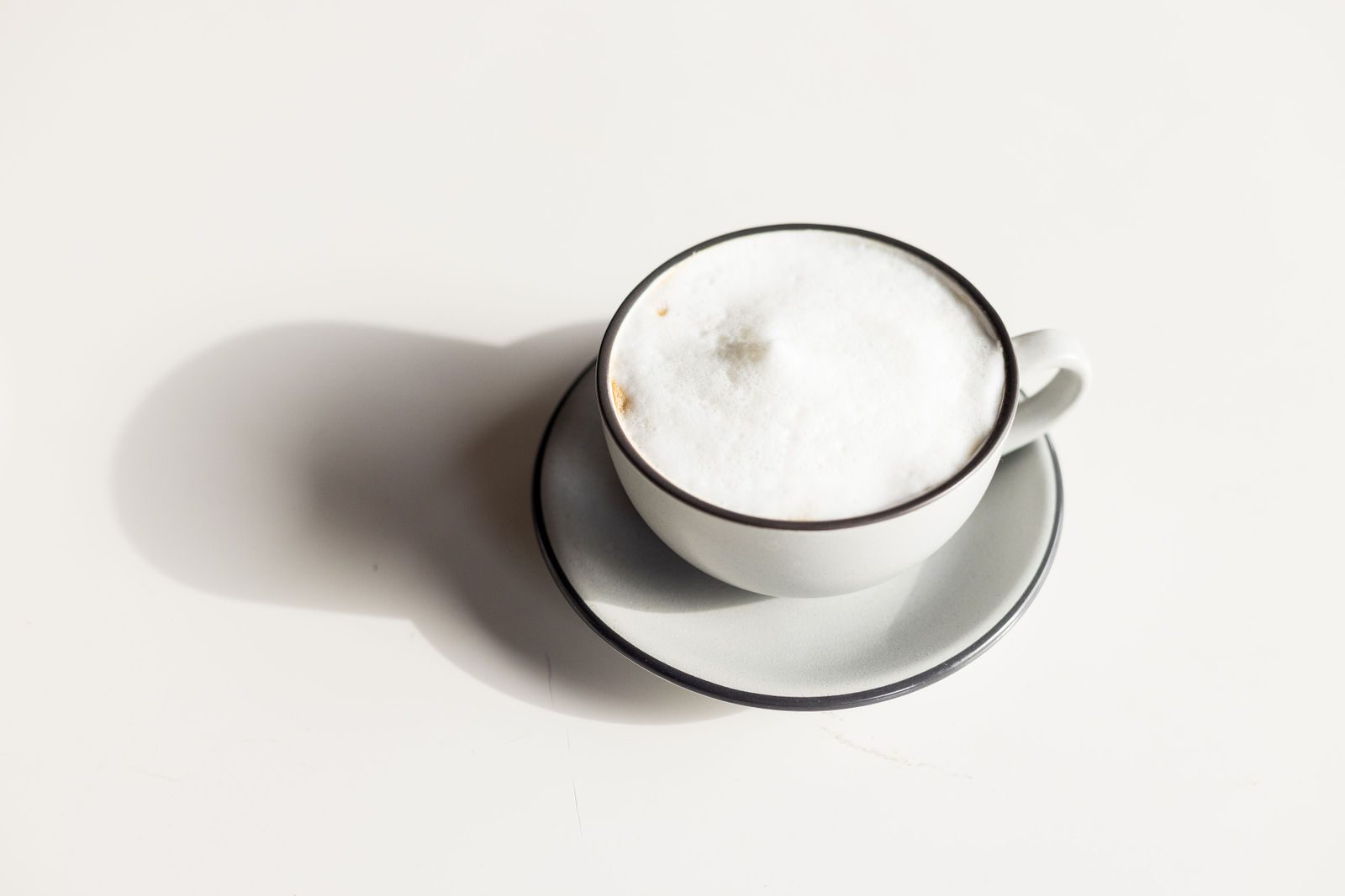 Cappuccino with a thick cap of white milk foam in a grey cup and saucer