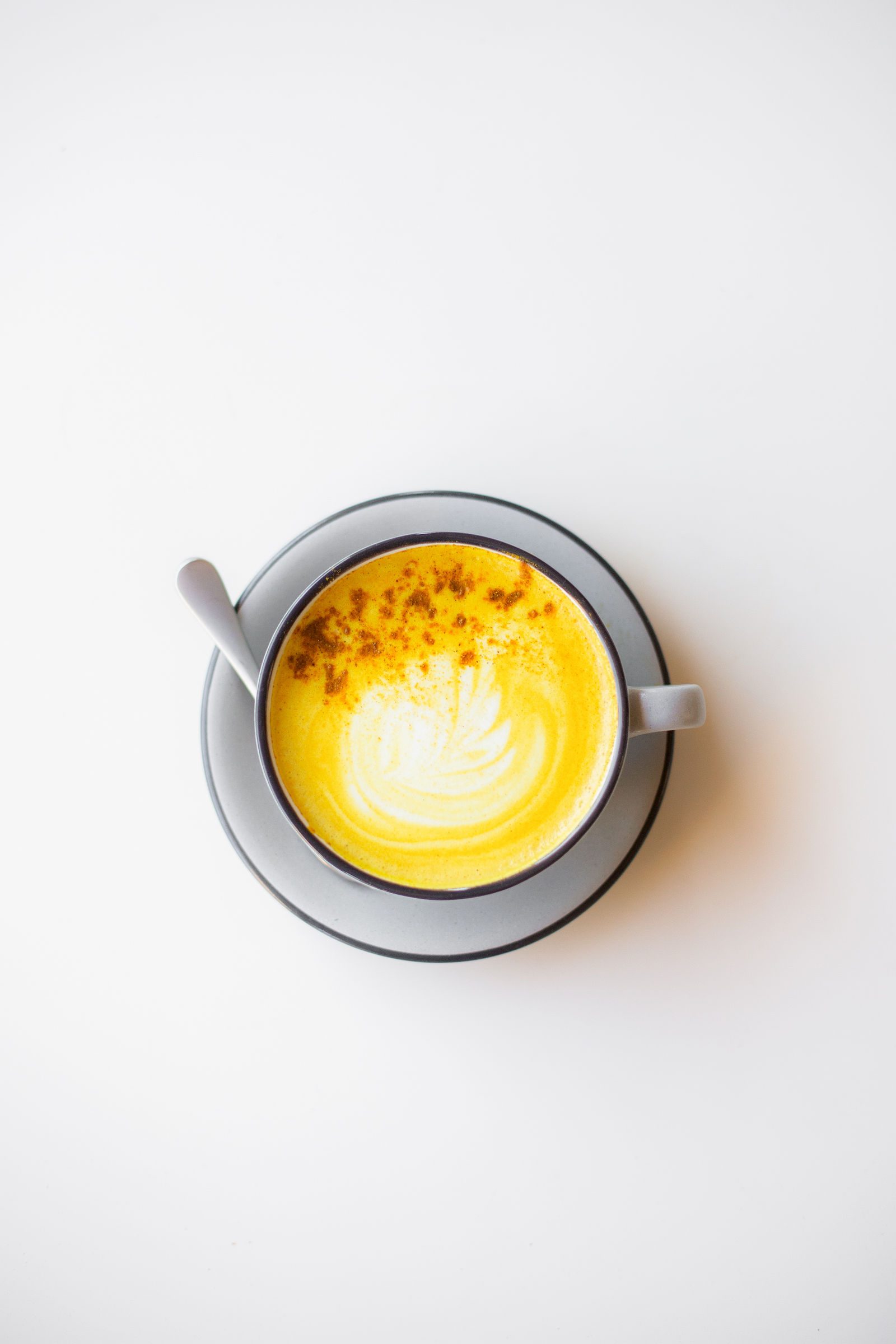 Golden milk latte with foam art and a dusting of spice in a grey cup