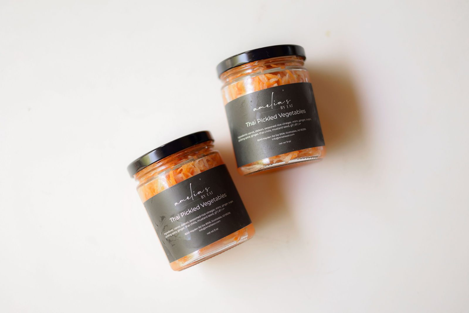 Two jars of Amelia's Thai Pickled Vegetables with carrot and daikon on white