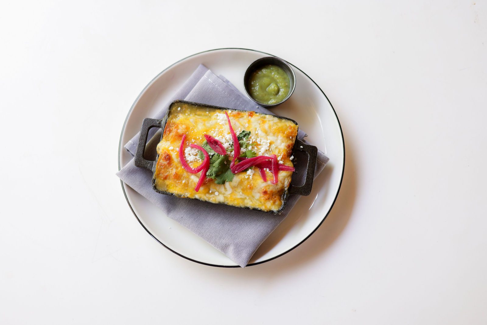 Stacey's chicken and rice enchilada with pickled onions and green chili sauce, baked in a cast-iron dish