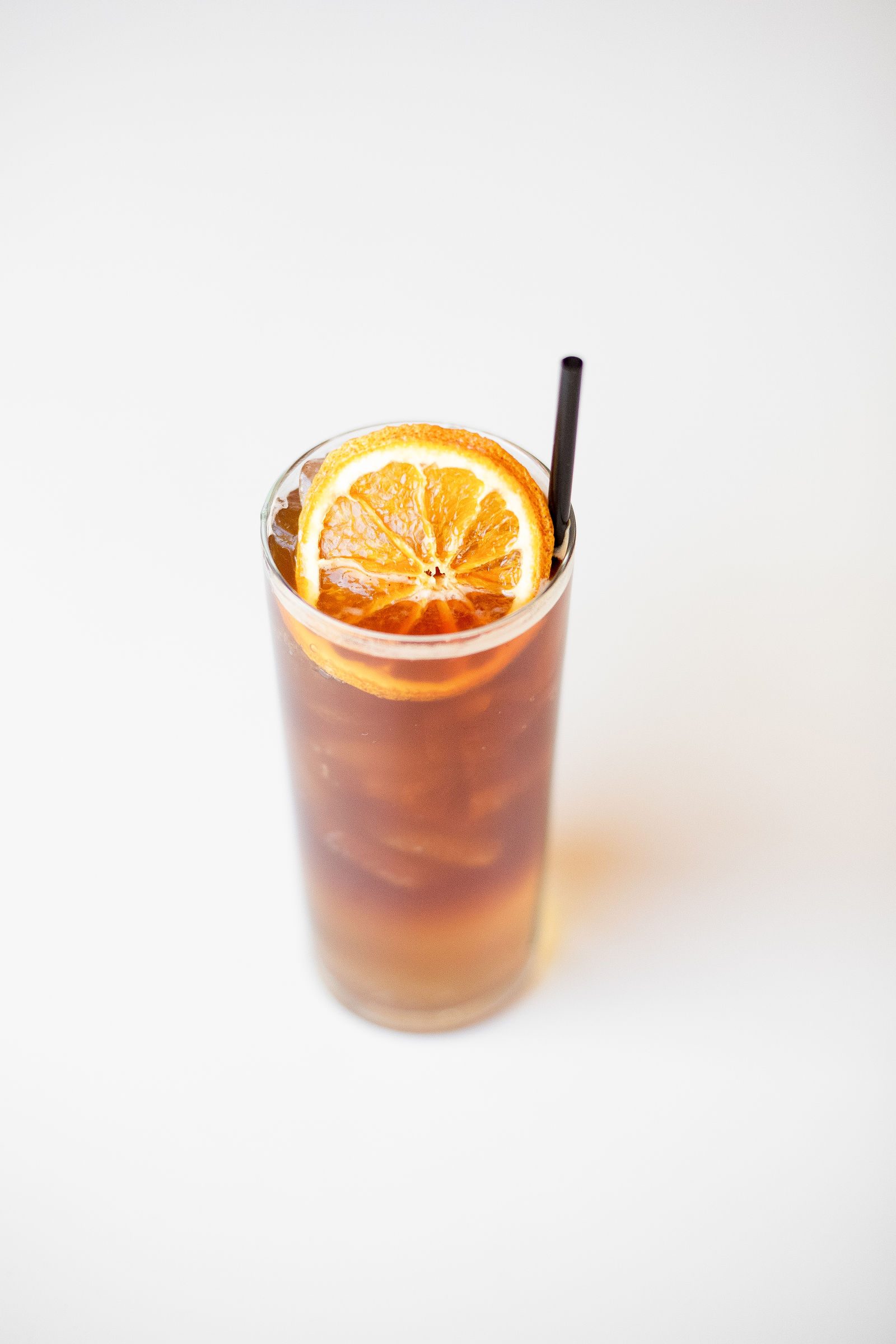 Iced orange cardamom espresso spritz in a tall glass with a dried orange wheel