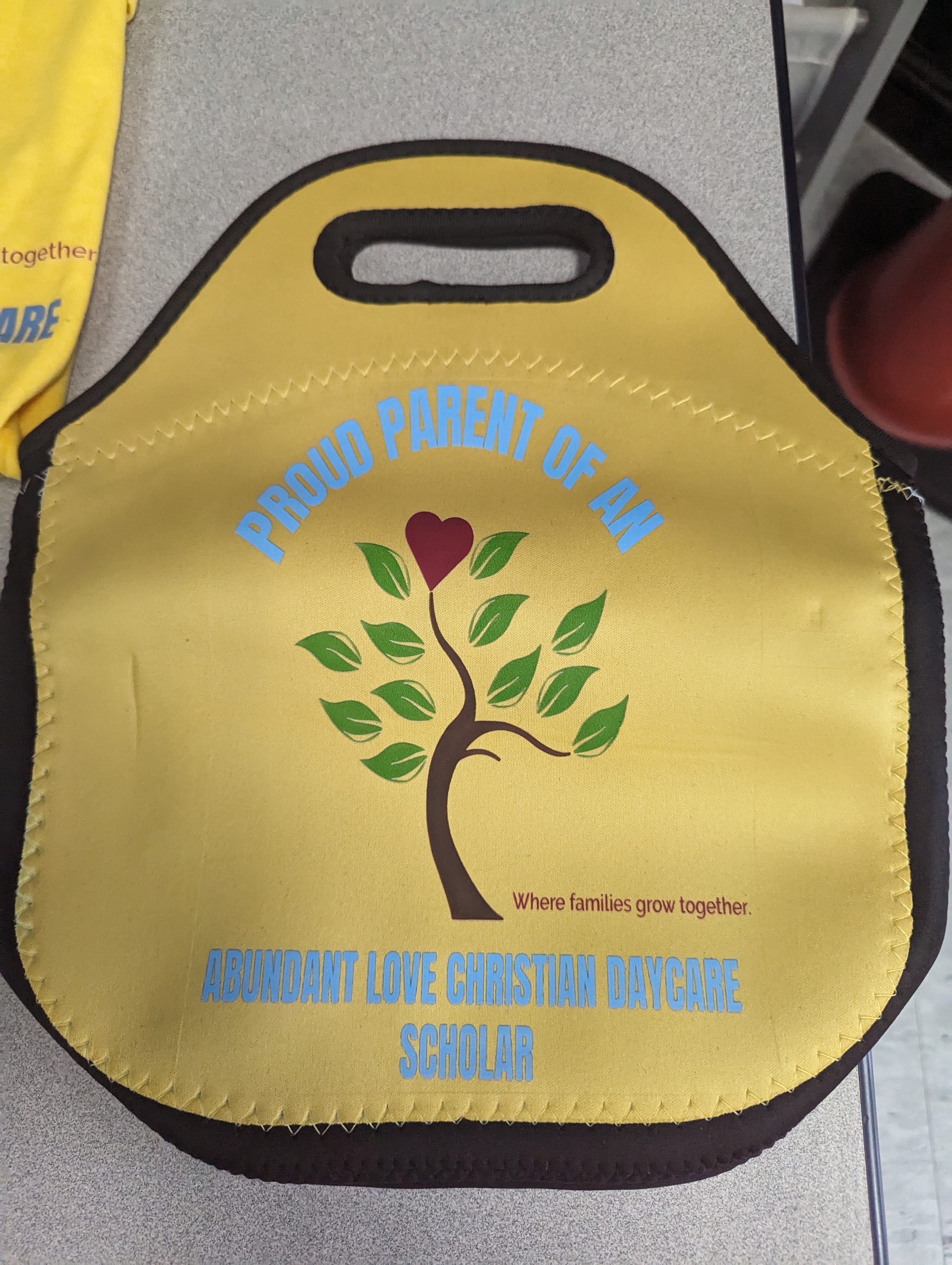Yellow lunch tote with "Proud Parent" in Carolina Blue and the school's logo.