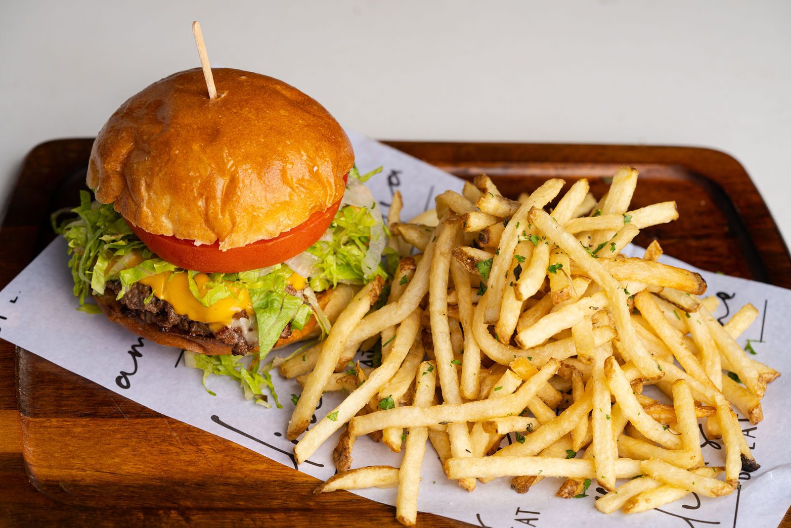 Amelia's Better Burger on brioche with tomato, shredded romaine, cheese and skinny fries