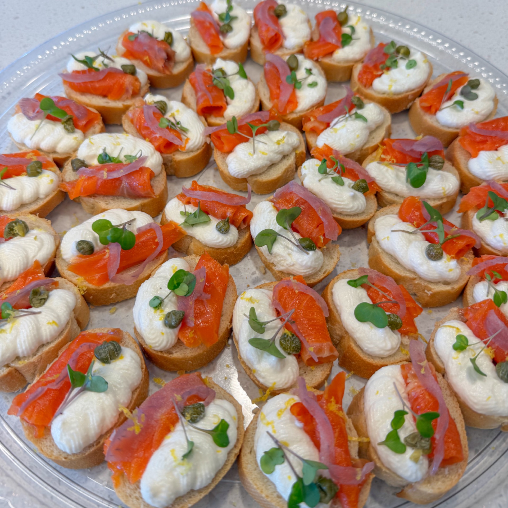 A platter of canapés with lemon ricotta and smoked salmon, capers and pickled onions