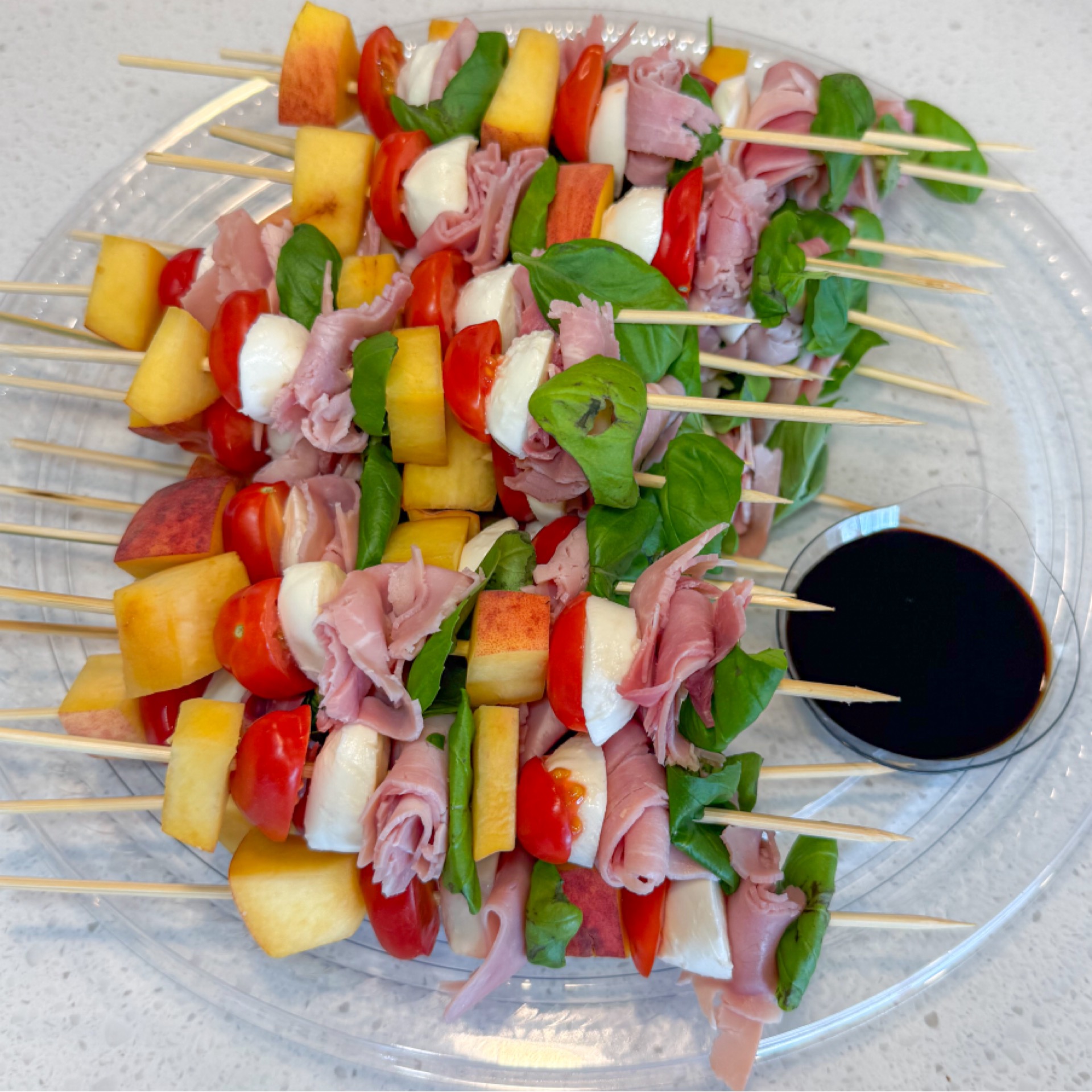 Platter of peach skewers, bocconcini, tomato, prosciutto and basil