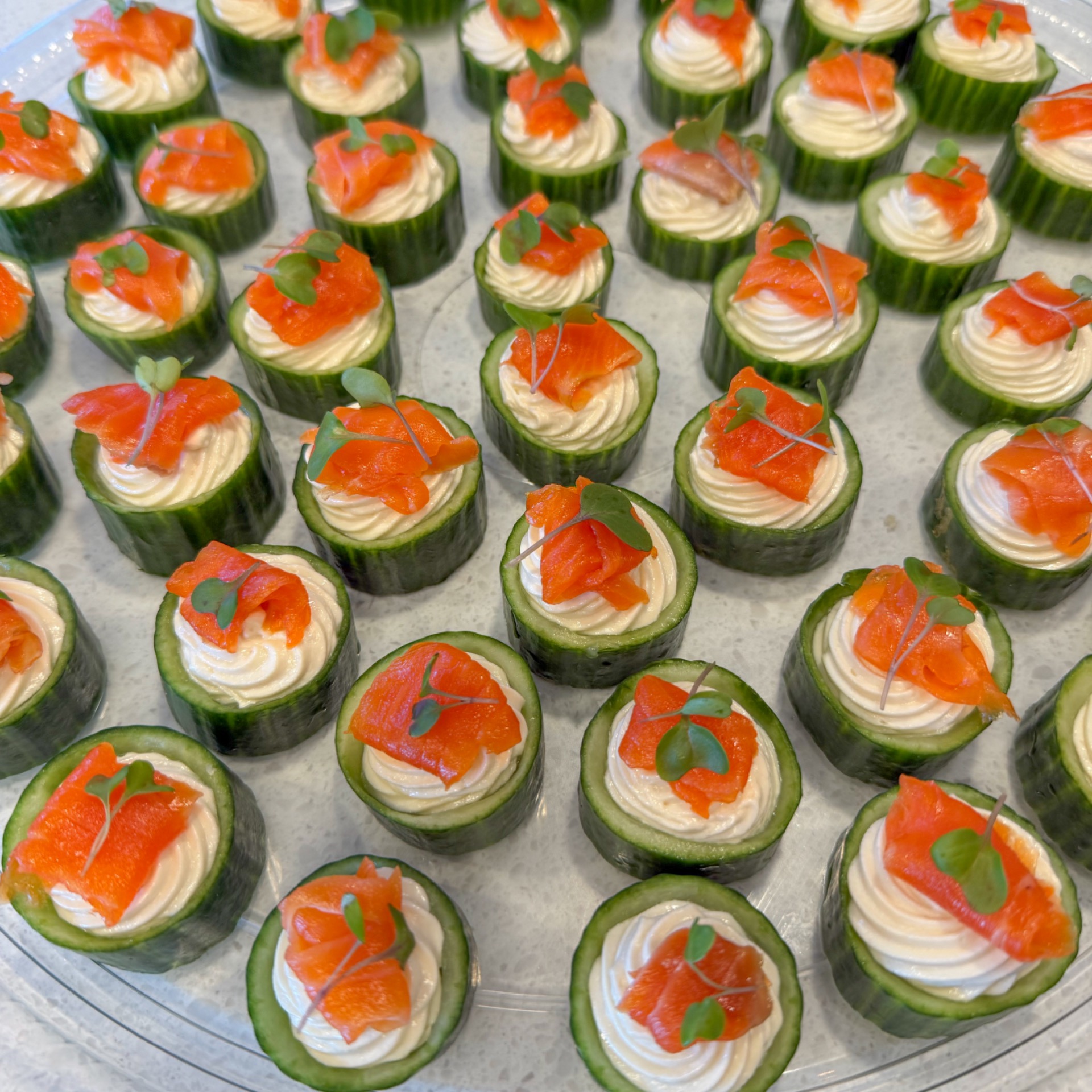 A platter of bite-sized cucumbers, maple sesame cream, and smoked salmon.