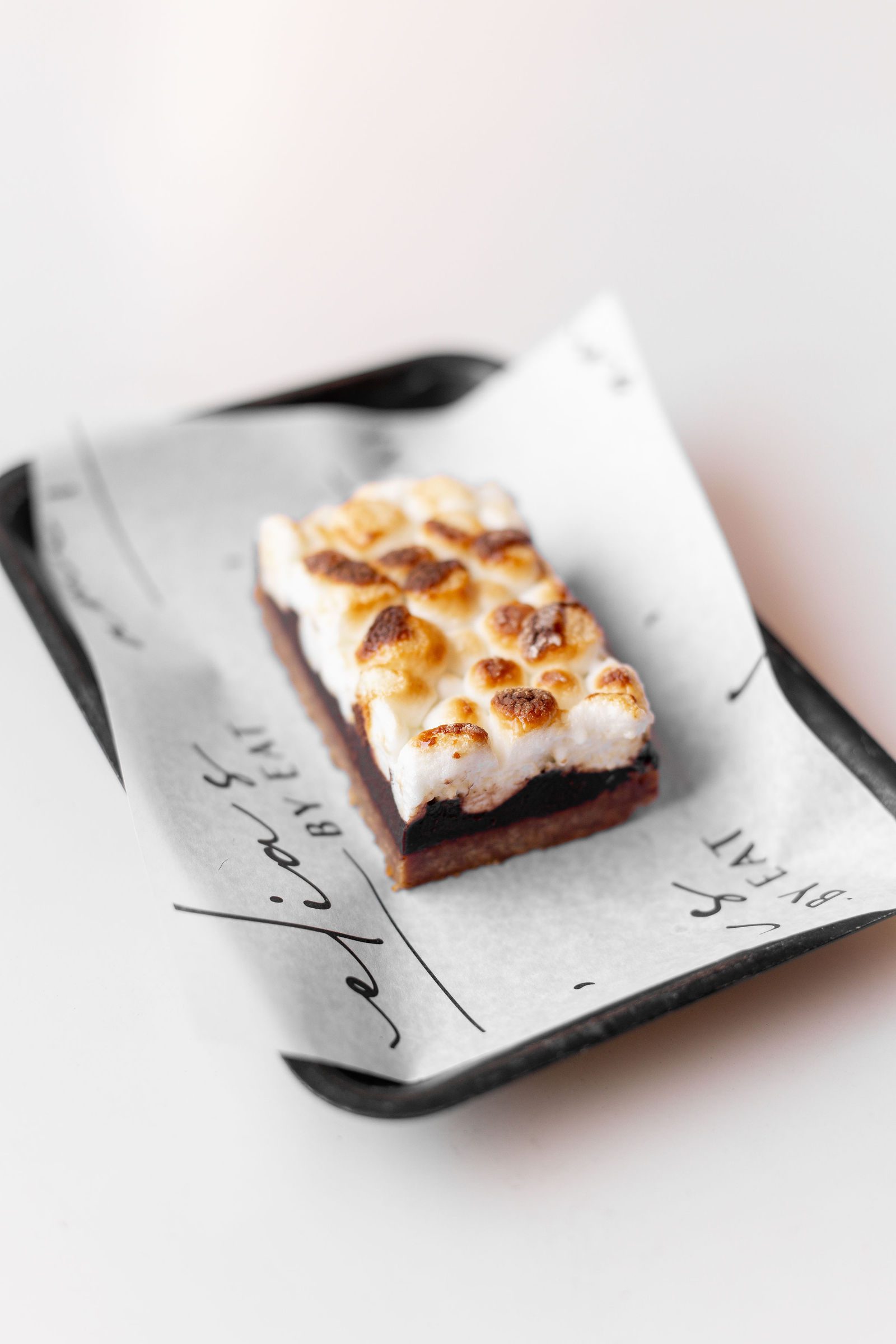 S'mores bar with toasted marshmallow over chocolate on Amelia's by EAT paper