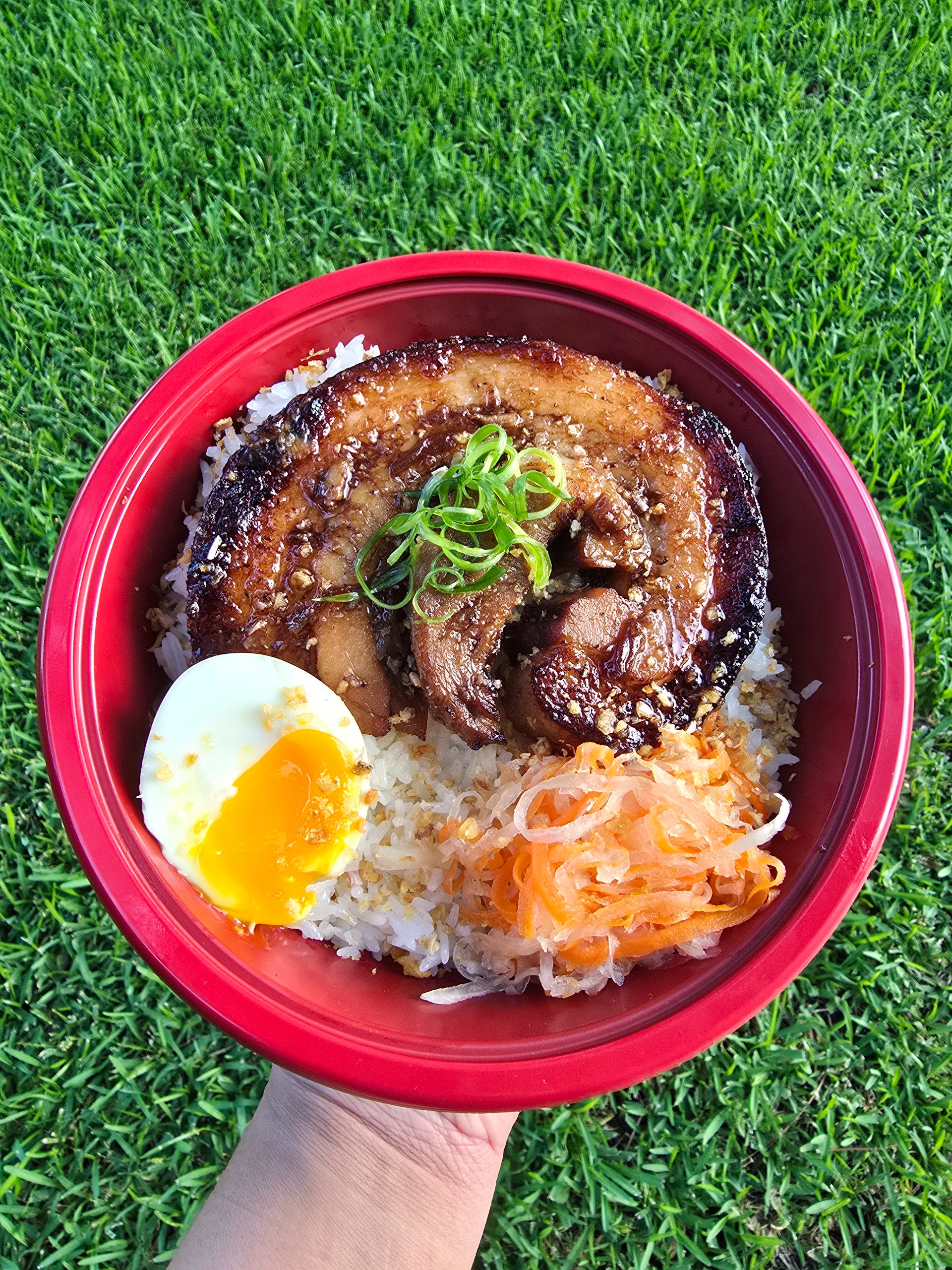 Pork chashu rice bowl with torched pork belly, mayak egg, and pickled vegetables over garlic rice
