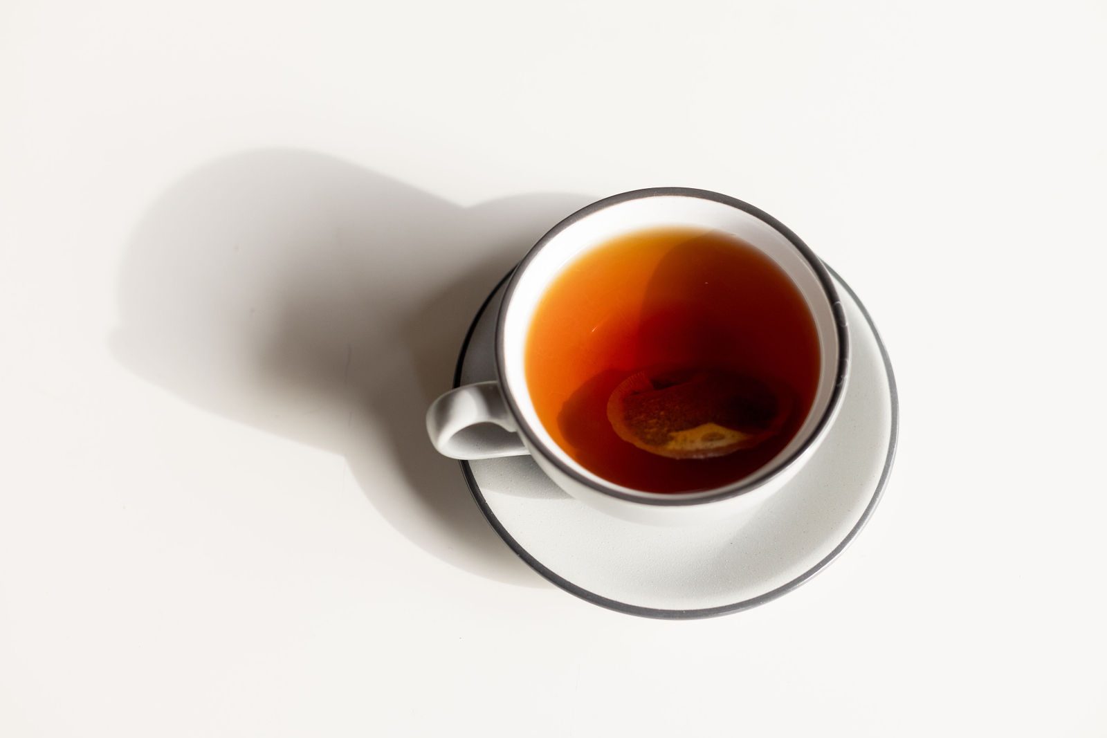 Cup of hot tea with a steeping tea bag in a white cup and saucer