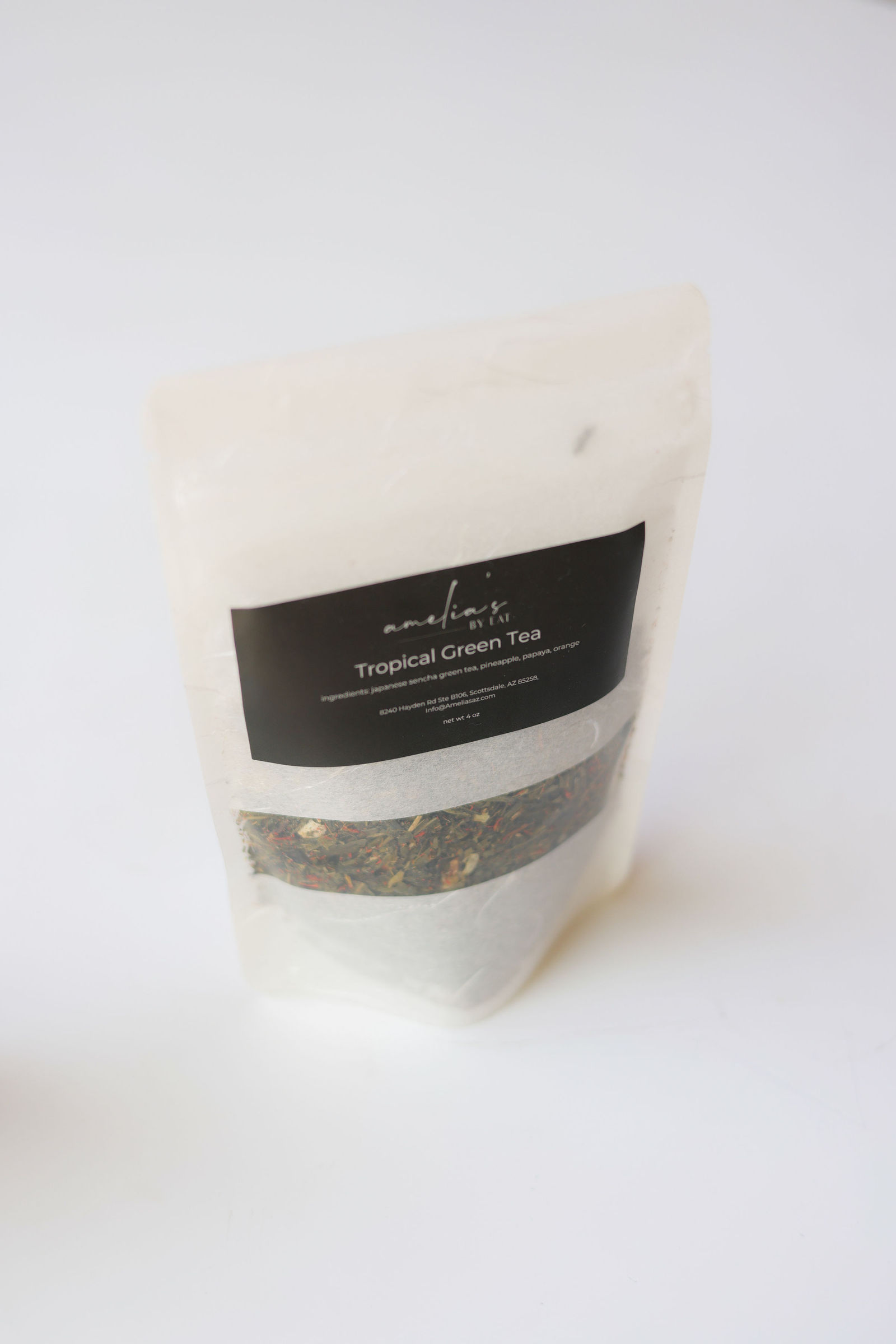Standing pouch of Amelia's Tropical Green Tea with loose leaf tea visible