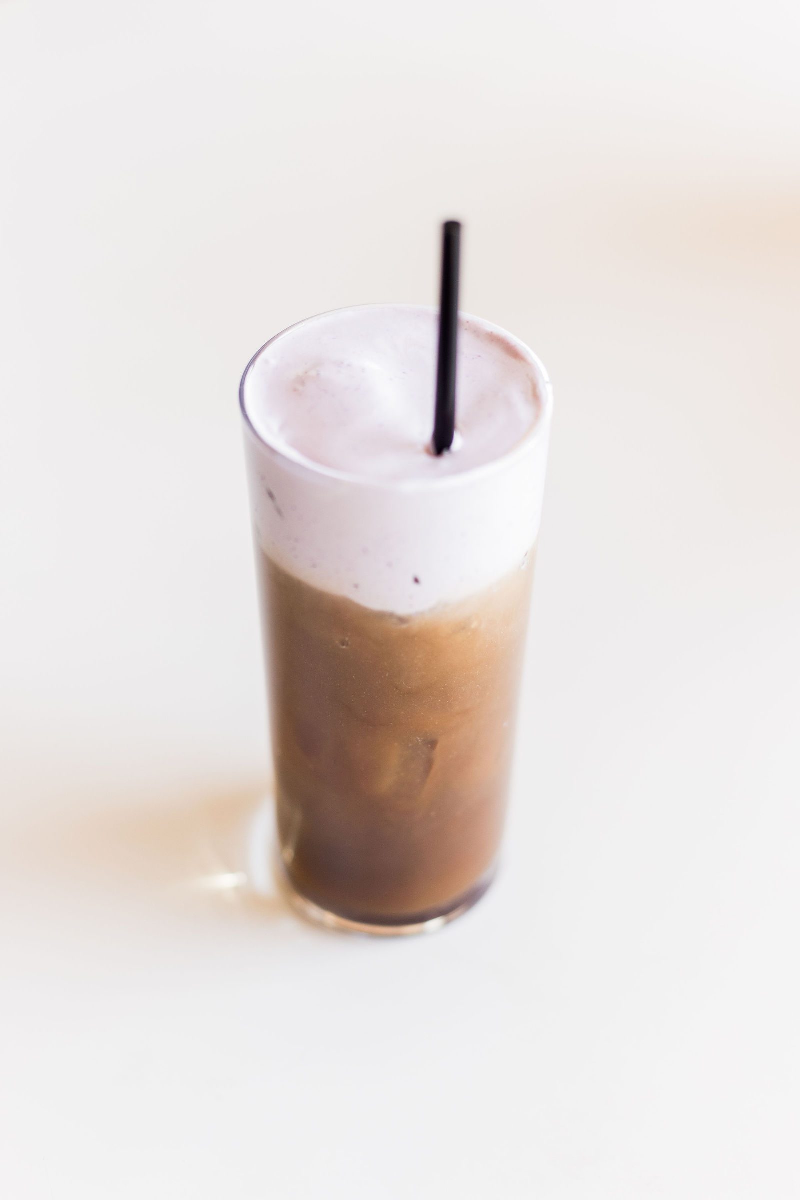 Cold foam cold brew in a tall glass with a black straw