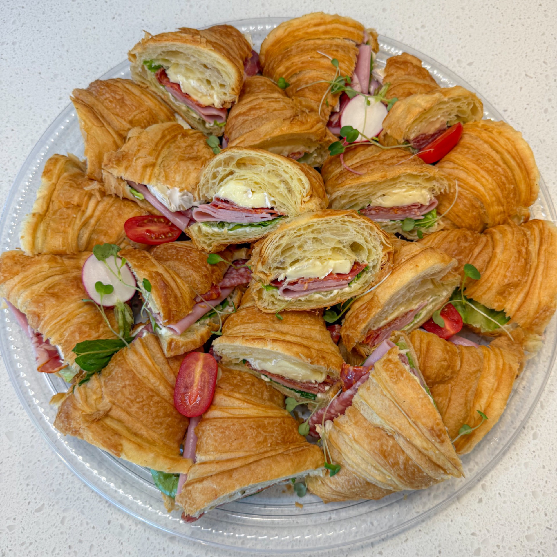 Platter of Italian croissant sandwiches with ham, salami, Boursin & brie