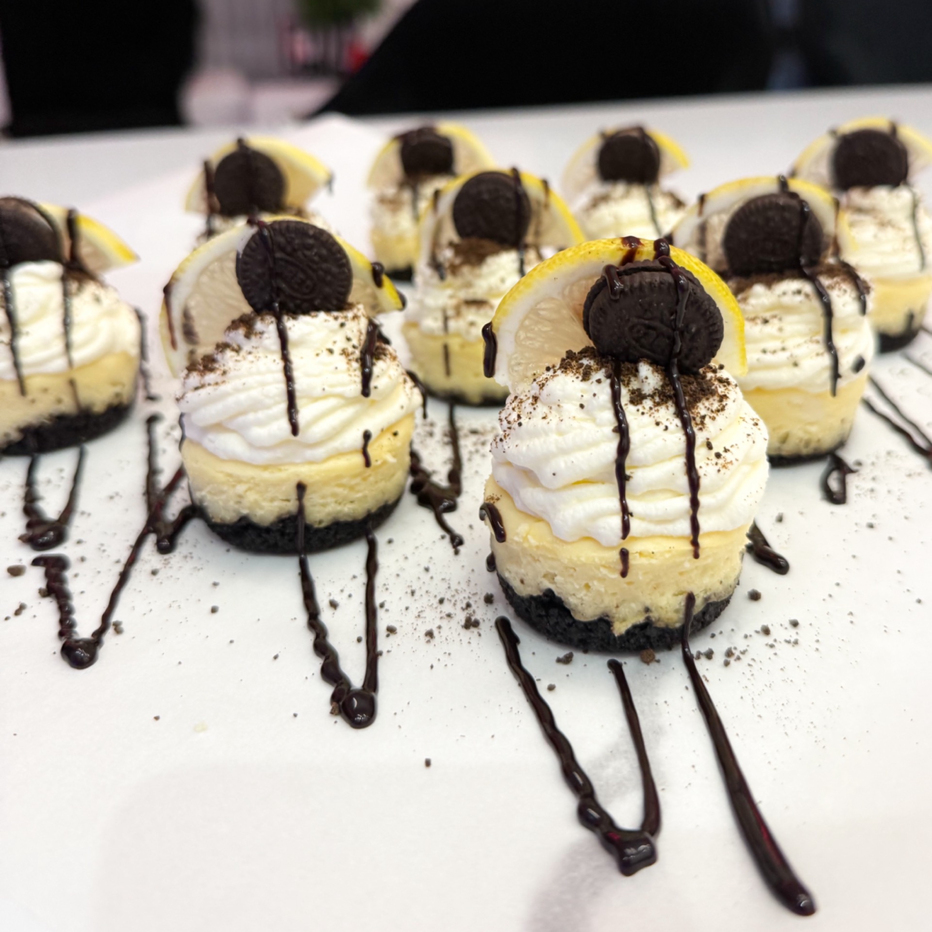 Tray of mini cheesecakes with whipped cream, chocolate and Oreo